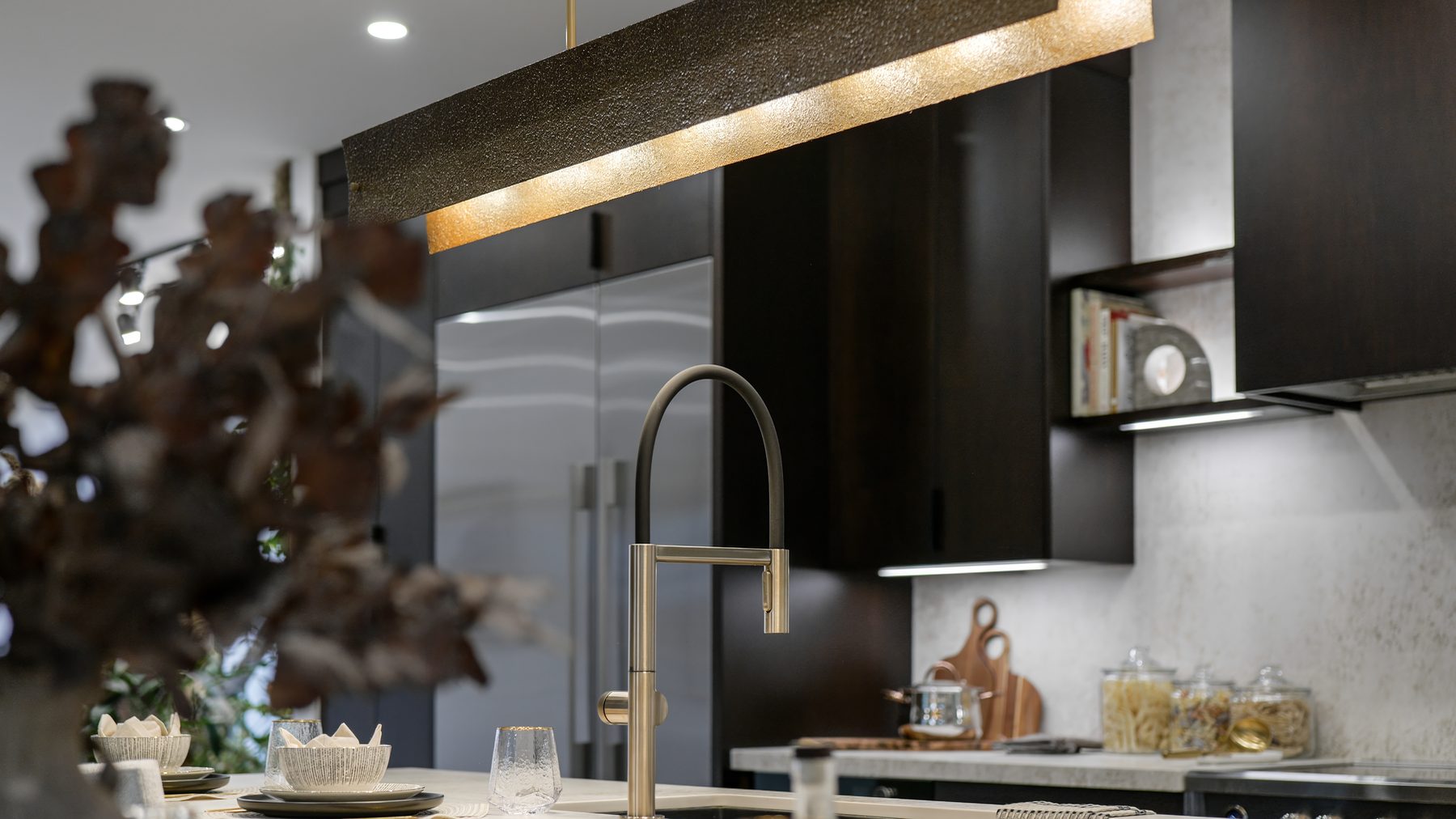 Custom kitchen island with brass faucet and linear pendant